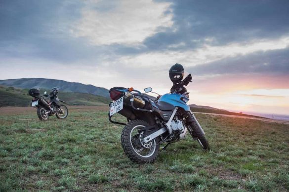 Two motorcycles parked on a grassy hill at sunset, ideal for motorcycle tours.