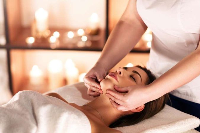 Relaxing facial massage in a day spa and a medical spa setting with candles