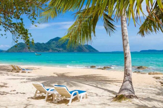 Empty lounge chairs on a quiet sandy beach facing a turquoise ocean in "an Off-Season Island Trip.jpg".