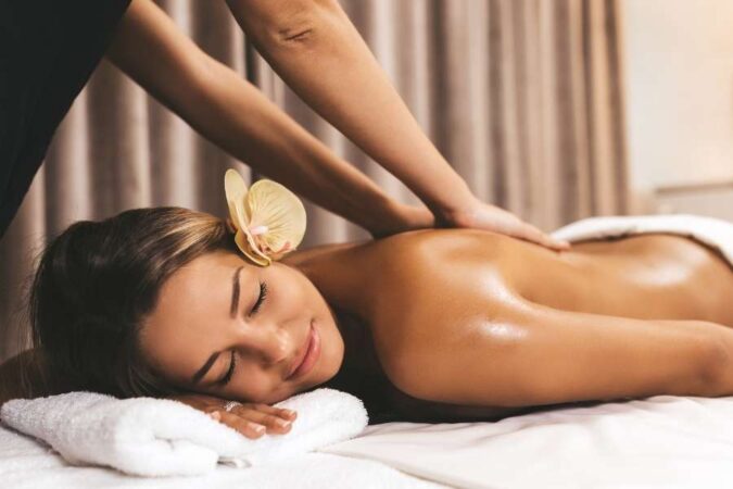 A smiling woman with an orchid in her hair receiving a Swedish Massage at a spa