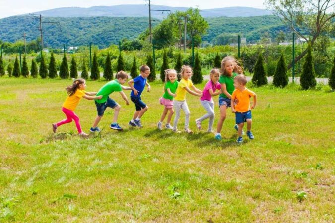 A group of happy children playing fun outdoor games together in a sunny green park.
